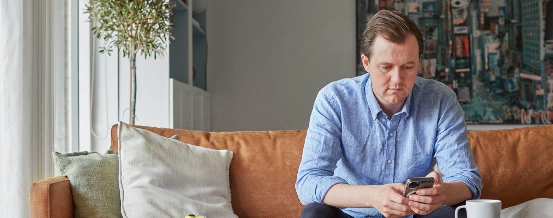 Mand i sofa kigger på sin telefon