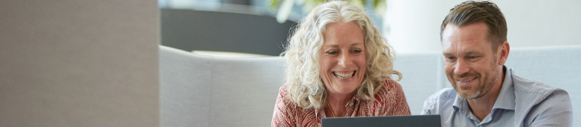 Mand og kvinde sidder i en sofa og kigger på en computer